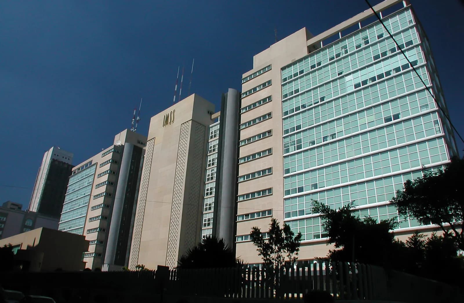 Fachada de un edificio del IMSS con grandes ventanales y el nombre de la institución visible