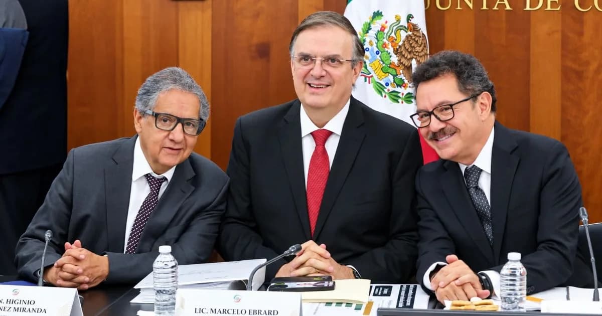 Tres funcionarios sentados a una mesa en una sala del Senado; Marcelo Ebrard aparece en el centro junto a la bandera de México