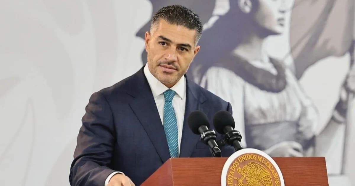 Omar García Harfuch, de traje azul marino y corbata turquesa, frente a un podio con el escudo nacional y dos micrófonos
