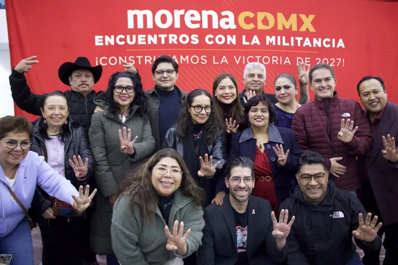 Grupo de integrantes de Morena CDMX posa frente a un fondo rojo de encuentros con la militancia y muestra cuatro dedos con las manos