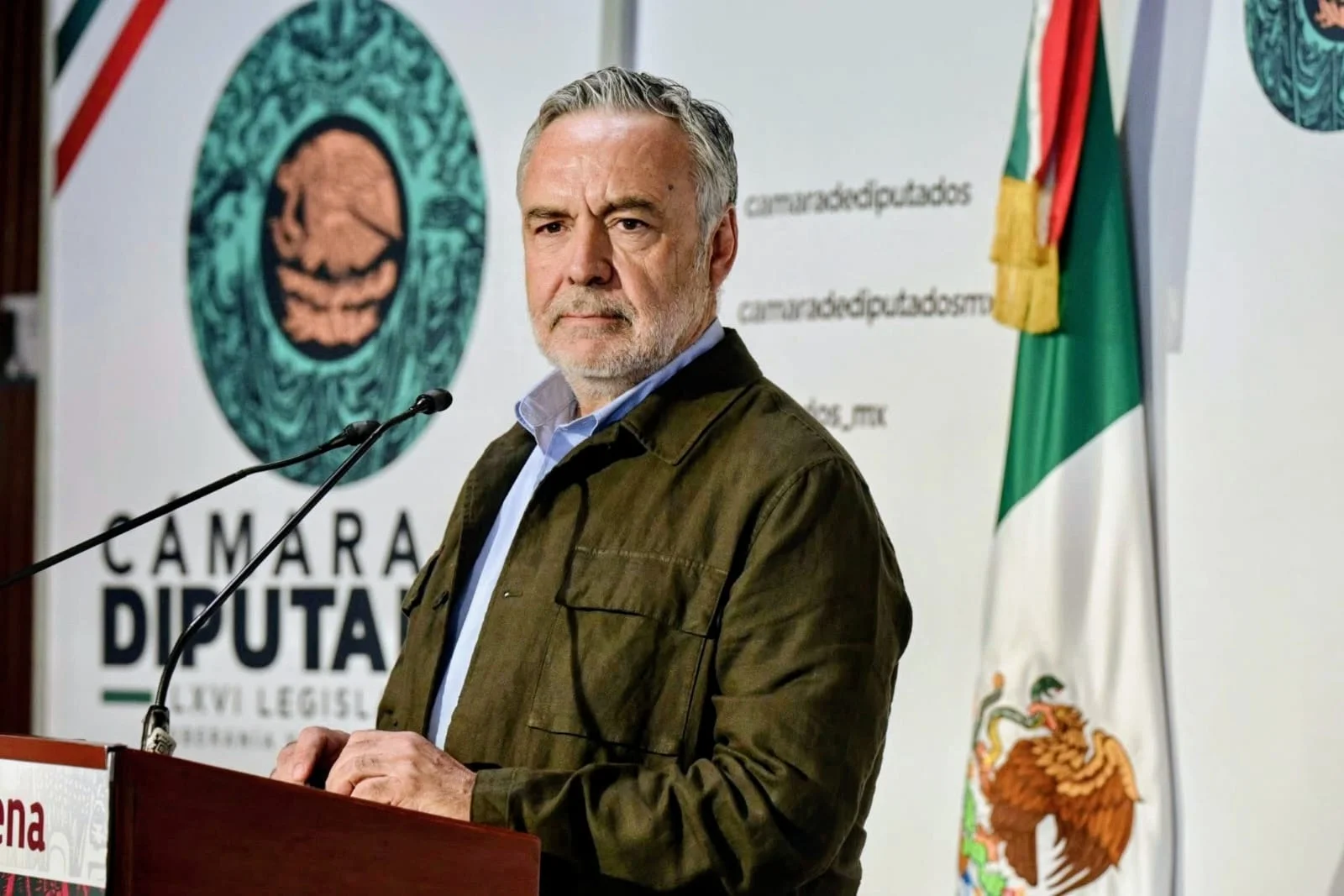 Alfonso Ramírez Cuéllar frente a micrófonos en la Cámara de Diputados, con la bandera de México al fondo