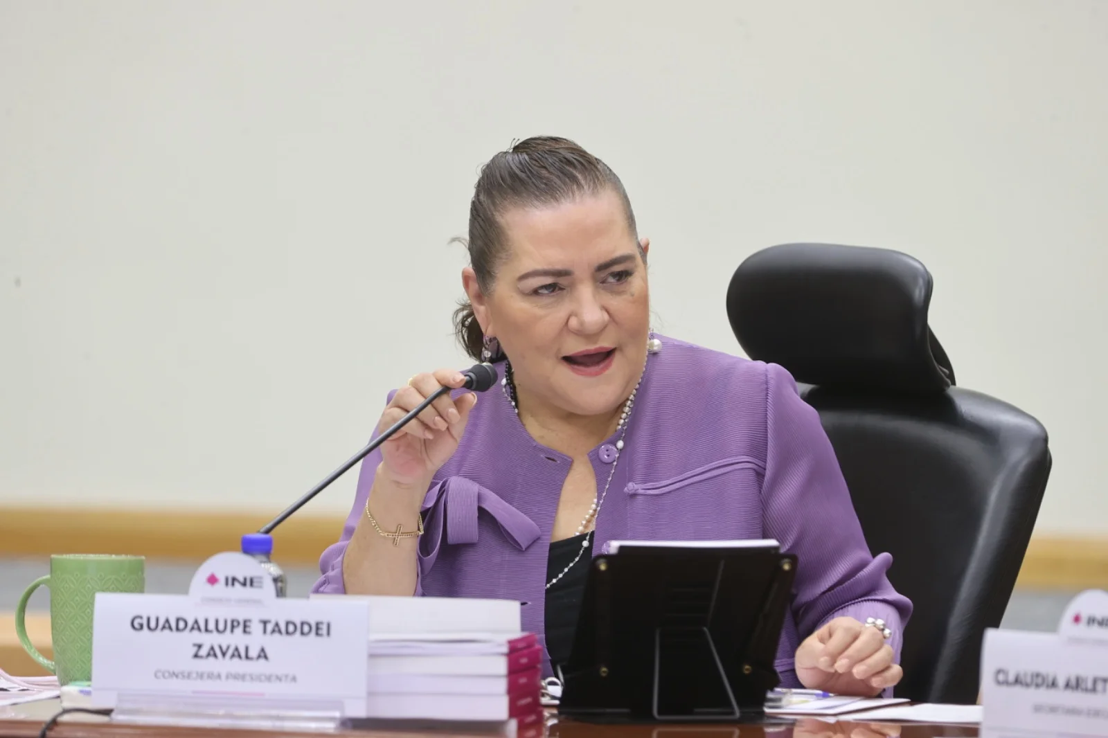 Guadalupe Taddei Zavala, con saco morado, habla ante un micrófono durante una sesión del INE.