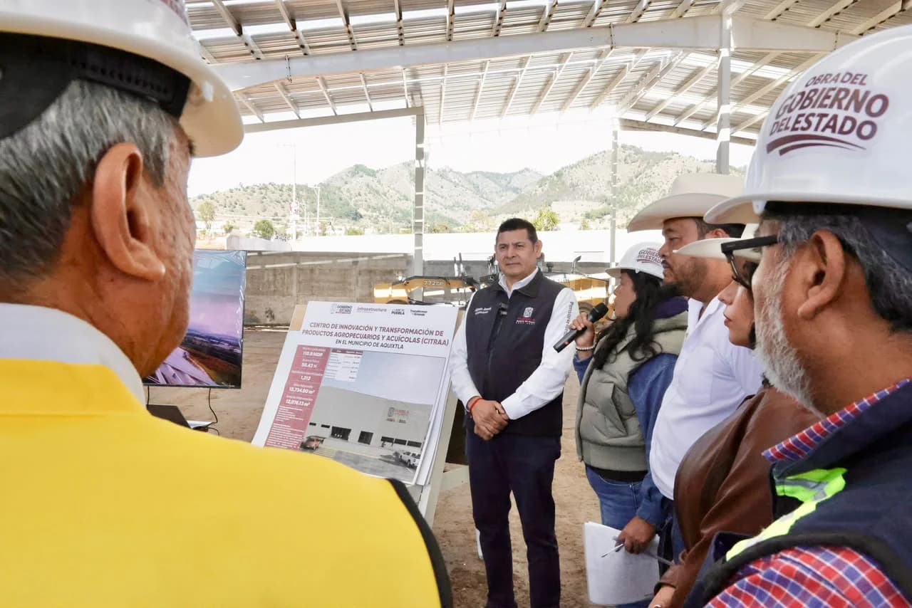 Alejandro Armenta y personal de obra observan la ficha técnica del centro agroindustrial CITRAA en Aquixtla, Puebla