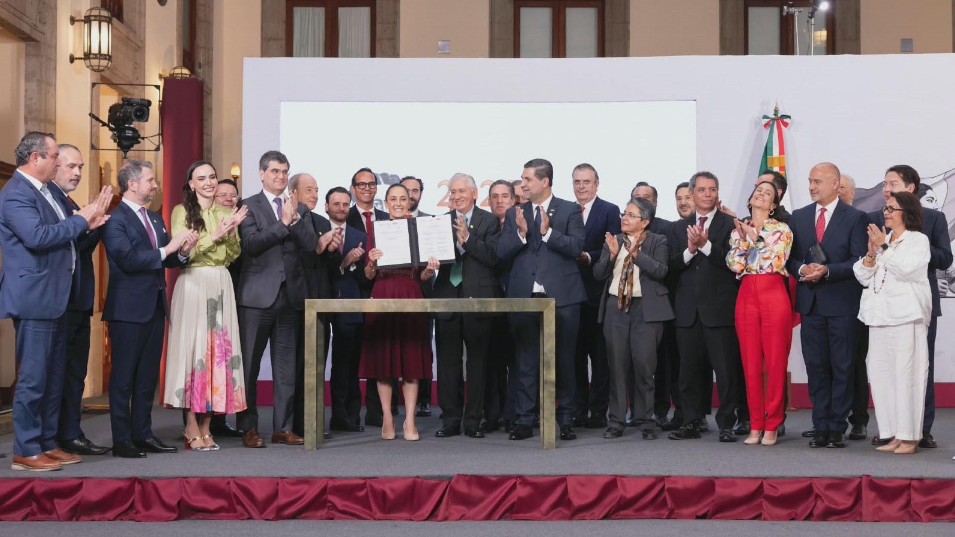 Funcionarios y representantes del sector reunidos durante un acto oficial, con una mujer al centro mostrando un documento.