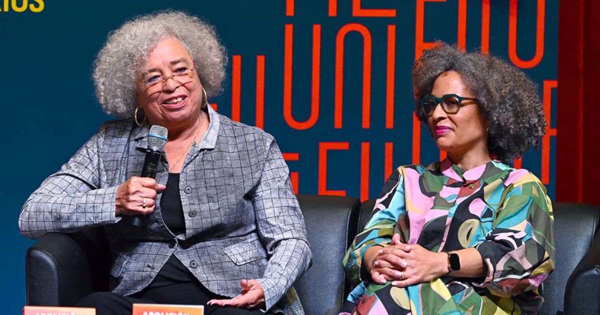 Angela Davis habla con un micrófono junto a Gina Dent durante el diálogo magistral en la Sala Miguel Covarrubias de la UNAM