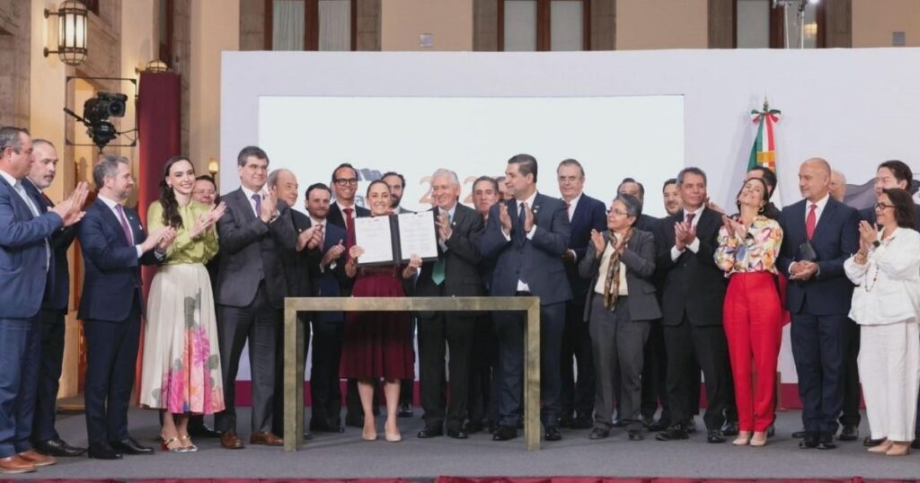 Funcionarios y representantes del sector reunidos durante un acto oficial, con una mujer al centro mostrando un documento.