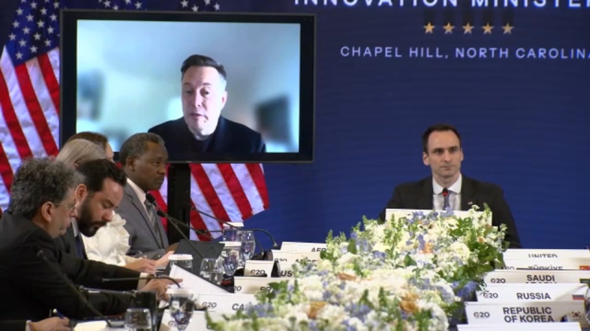 Elon Musk interviniendo virtualmente en el G20 Innovation Ministerial desde una pantalla durante su participación en Chapel Hill
