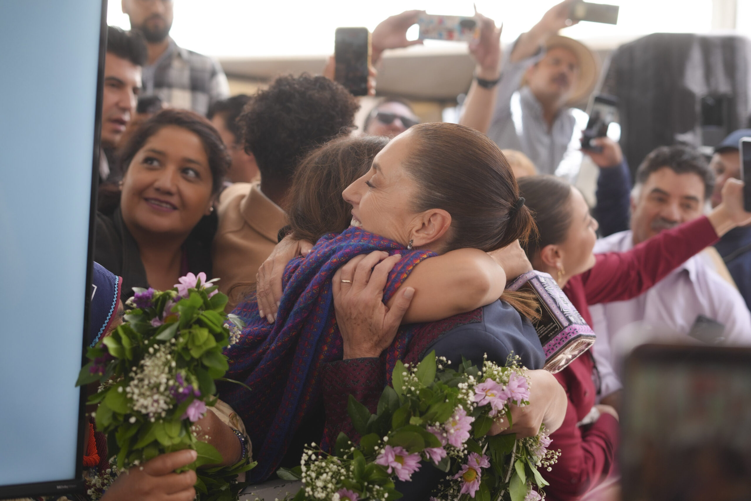 Abrazo entre asistentes durante un evento de apoyos en Zacatecas