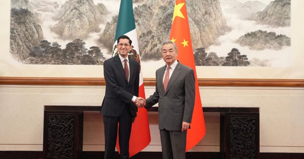 Roberto Velasco y Wang Yi estrechan la mano ante las banderas de México y China