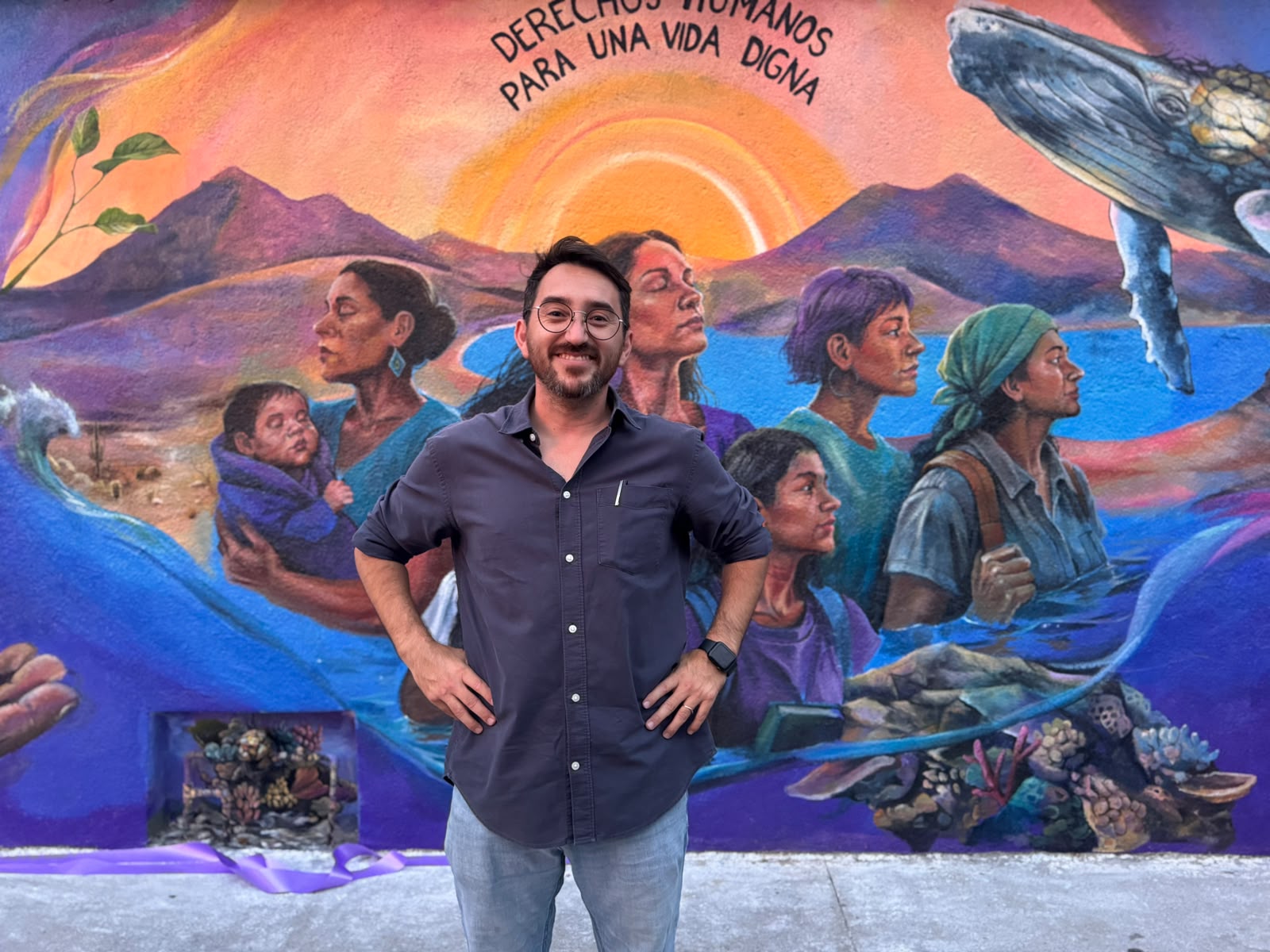 Frank Aguirre frente a un mural comunitario dedicado a los derechos humanos y la vida digna