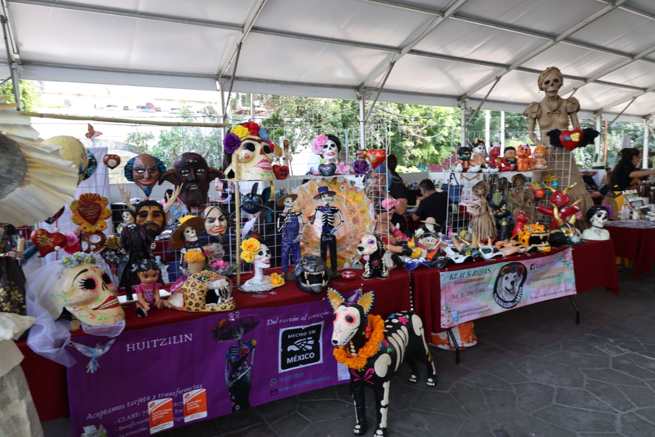 Una mujer y un hombre conversan frente a un puesto con productos y materiales exhibidos durante el Festival de Reciclaje Inclusivo.
