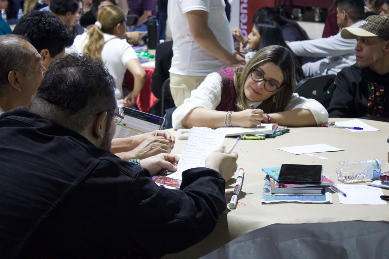 Asistentes dialogan alrededor de una mesa durante el encuentro de Morena CDMX