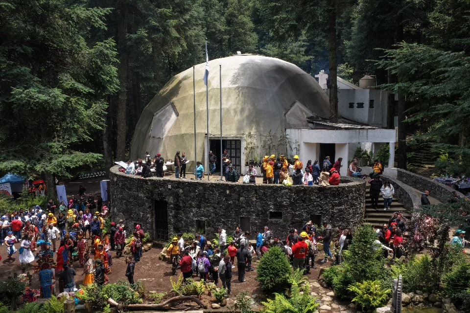 Visitantes reunidos junto a una construcción de forma abovedada en una zona boscosa