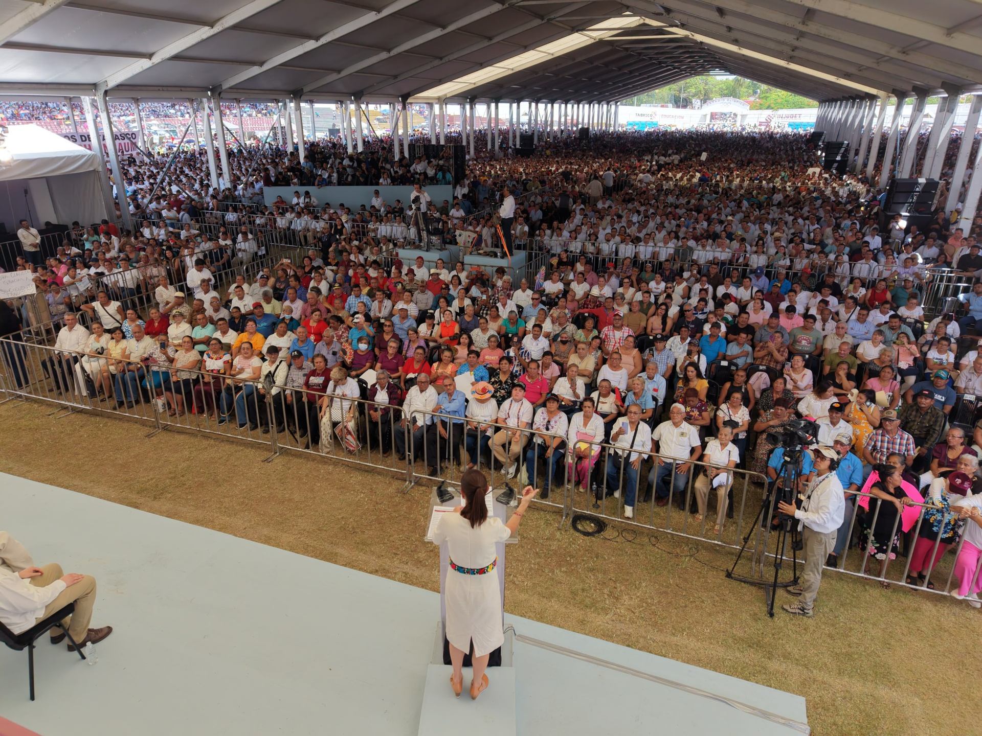 Claudia Sheinbaum habla desde un escenario ante una multitud reunida bajo una estructura techada durante un acto público en Tabasco.