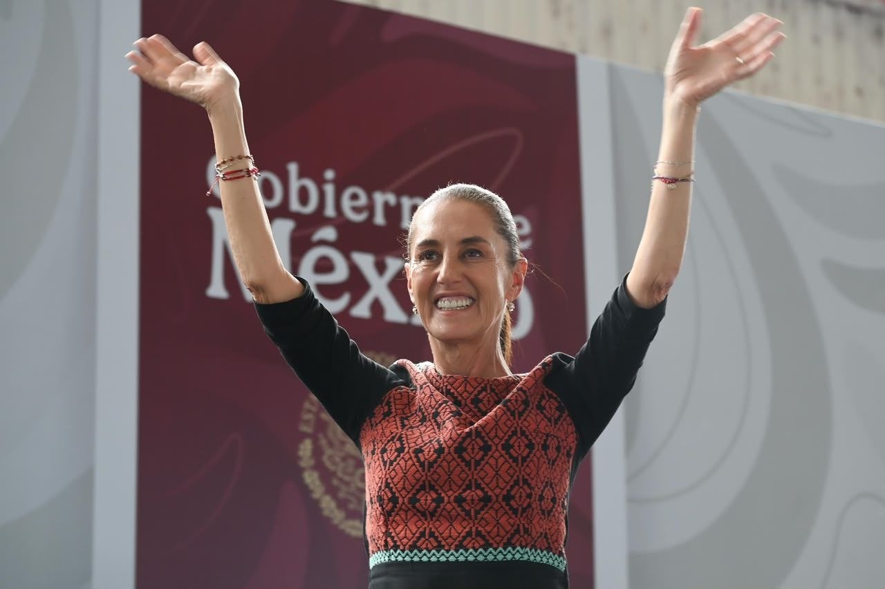 Mujer sonríe con ambos brazos levantados durante un evento público