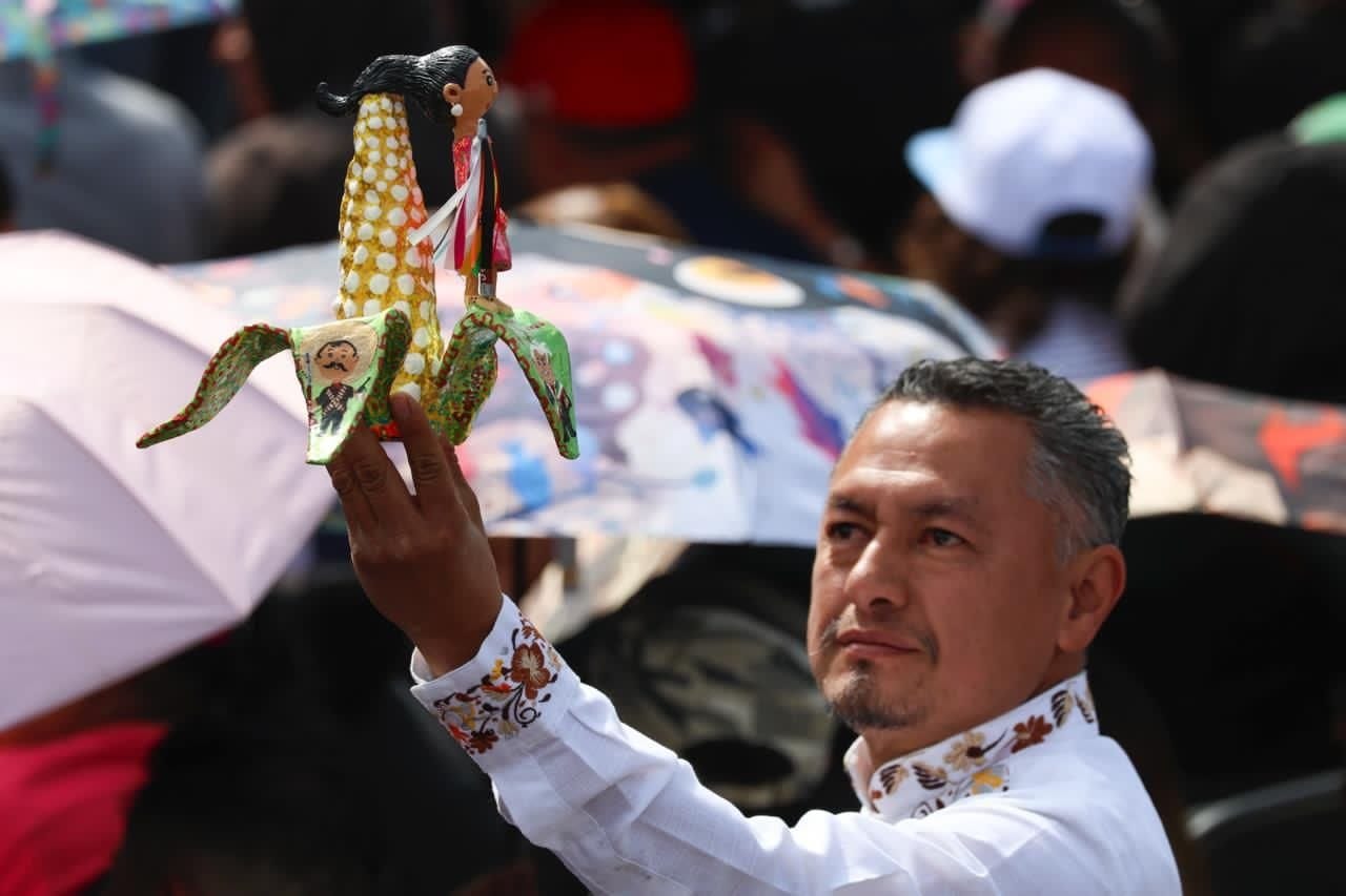Asistente muestra una figura alusiva a Claudia Sheinbaum durante el acto en el Zócalo