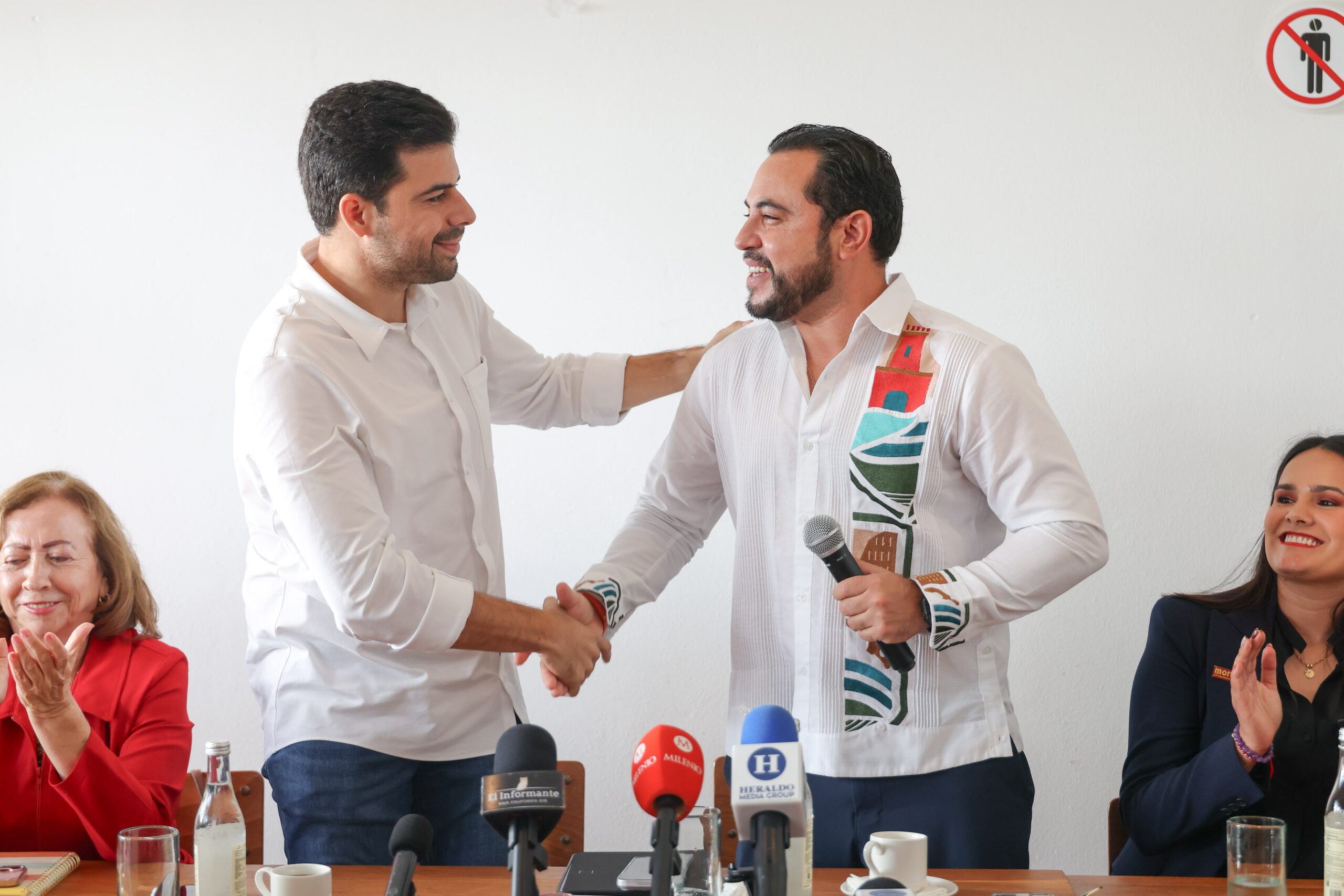 Manuel Cota y Christian Agúndez se saludan de mano durante una conferencia en Baja California Sur