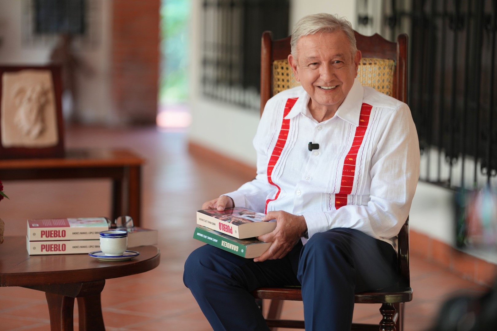 Andrés Manuel López Obrador sentado con ejemplares de Pueblo y Grandeza