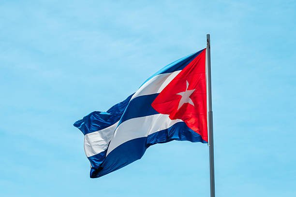 Bandera de Cuba ondeando contra un cielo azul.
