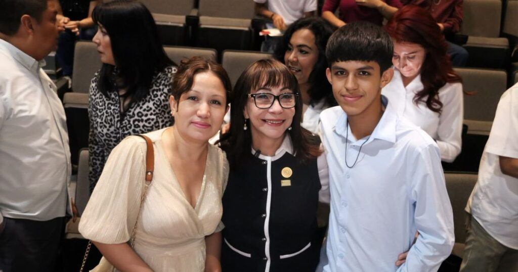 Blanca Anzaldúa posa con una mujer y un joven durante un encuentro en un auditorio