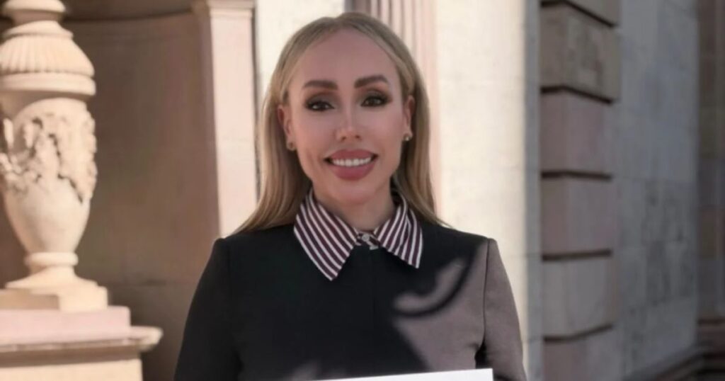 Brenda Ríos sostiene una solicitud de registro de Morena frente a un edificio de piedra.