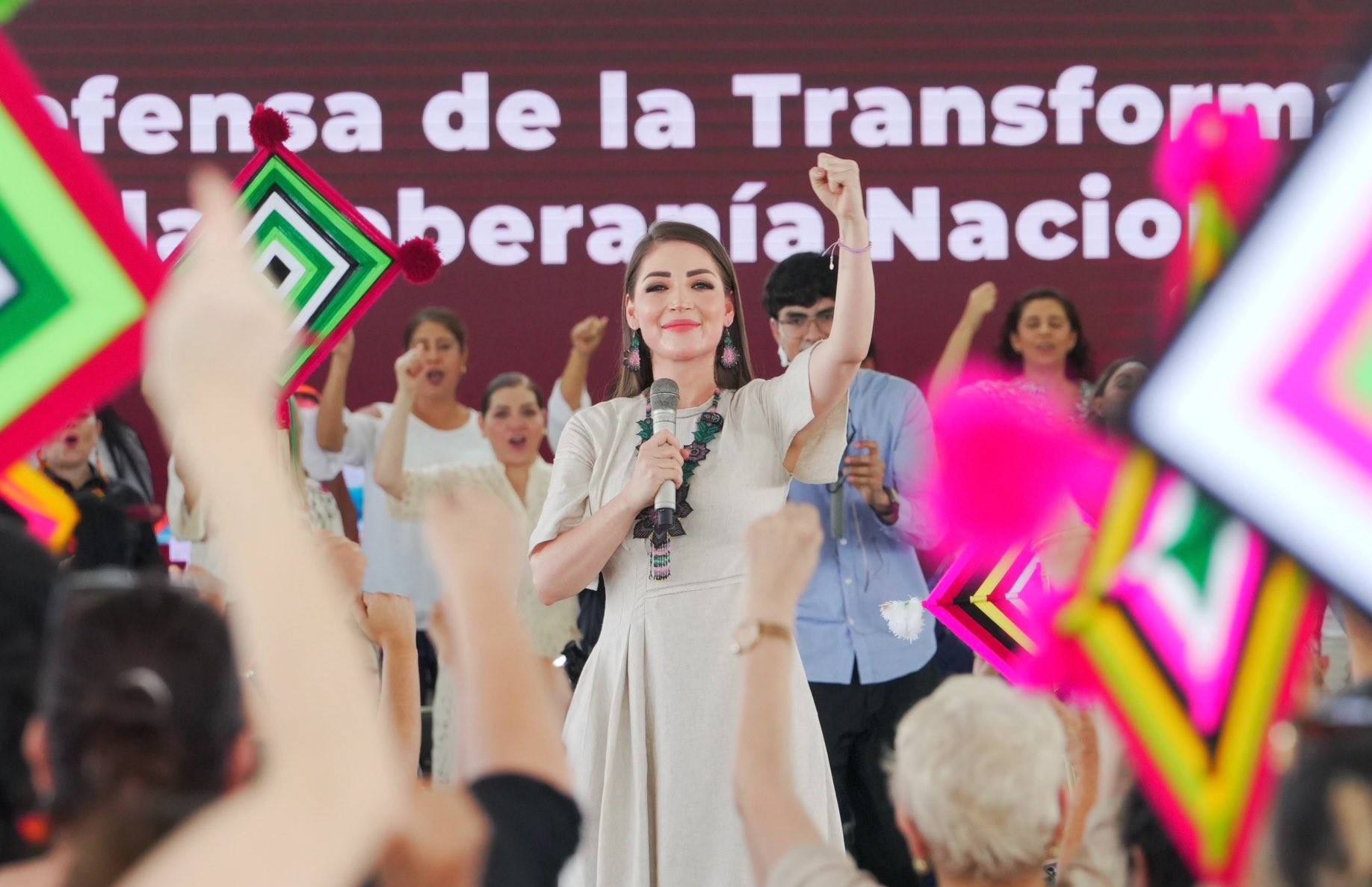 Jasmine Bugarín sostiene un micrófono y levanta el puño frente a simpatizantes