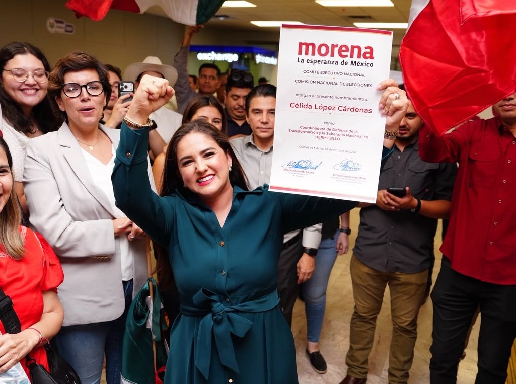 Mujer sostiene un nombramiento de Morena y levanta el puño durante un encuentro con simpatizantes