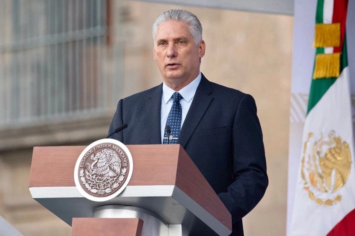 Hombre con traje habla desde un podio oficial con una bandera de México al fondo