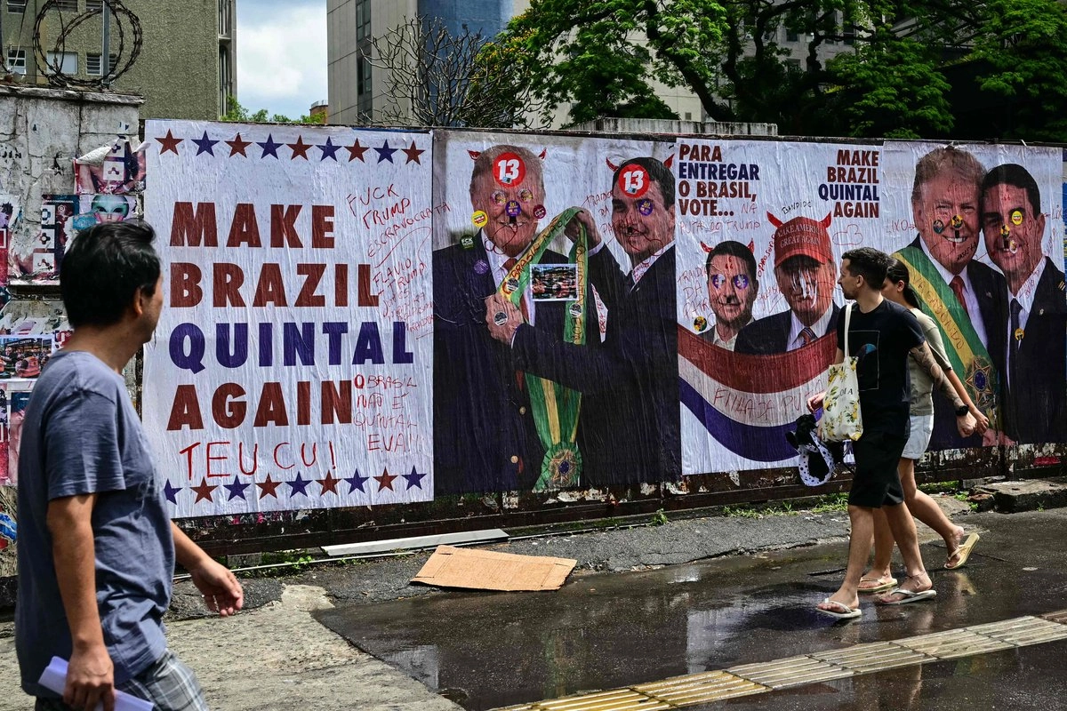 Personas caminan frente a carteles políticos intervenidos con grafiti en una calle de Brasil