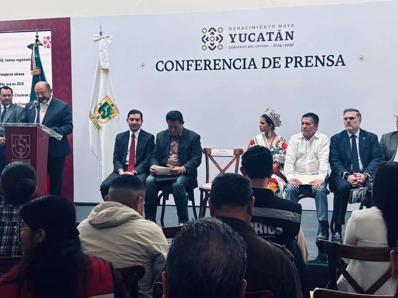 Conferencia de prensa del Gobierno de Yucatán con autoridades e invitados sentados frente a un estrado.
