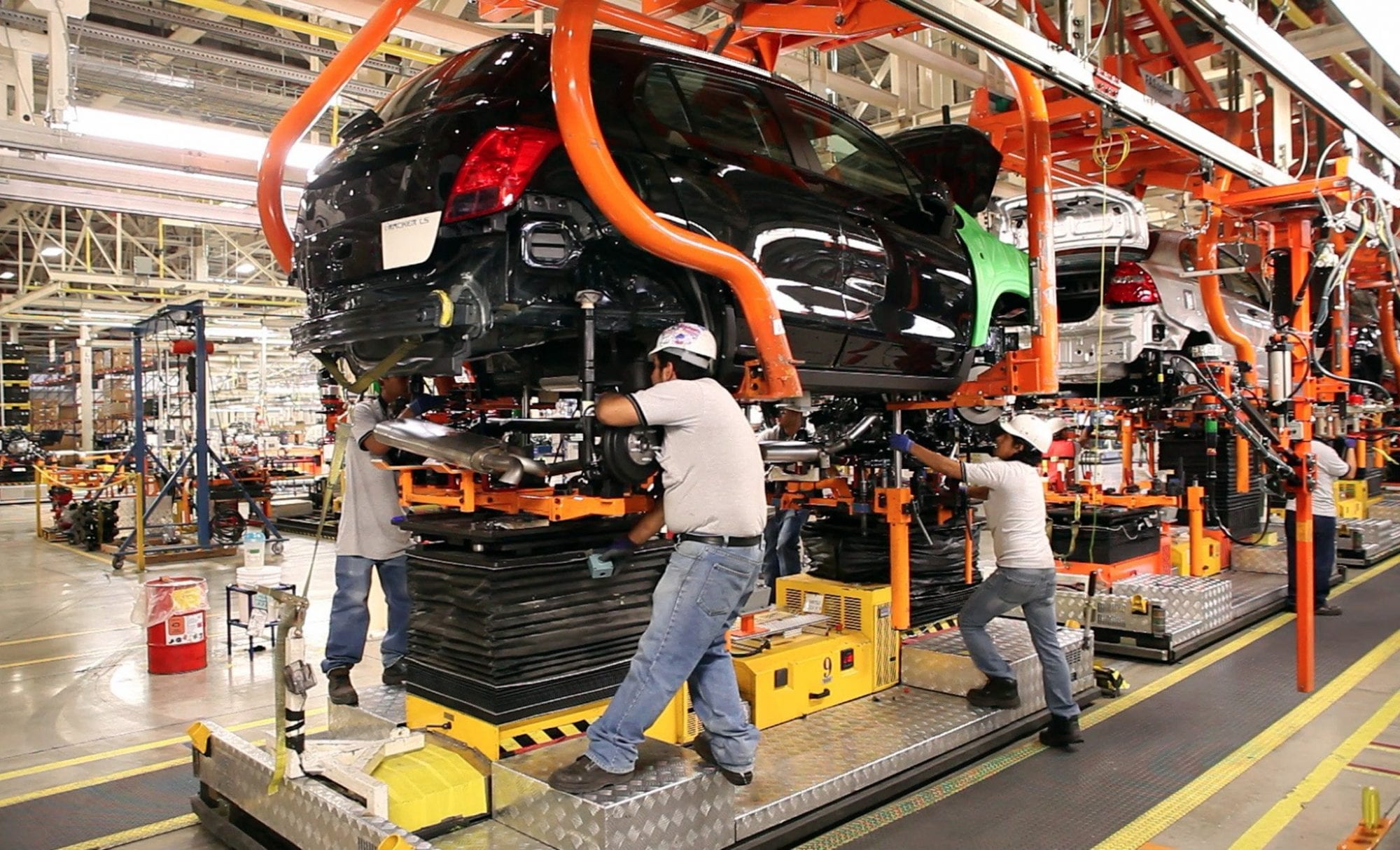 Trabajadores realizan labores de ensamblaje en una línea de producción automotriz