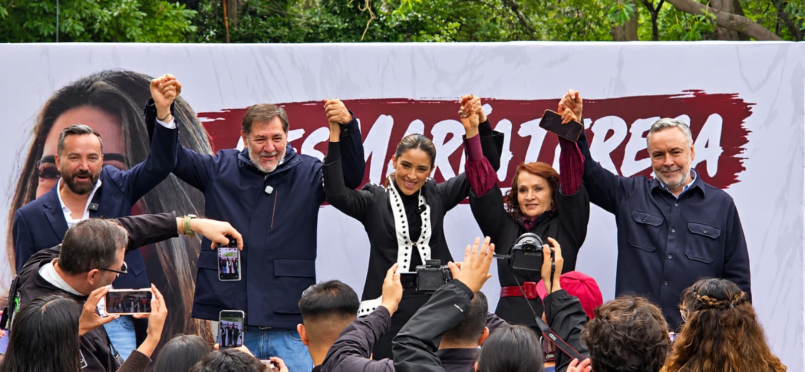 María Teresa Ealy levanta la mano junto a asistentes durante un acto público en Miguel Hidalgo.