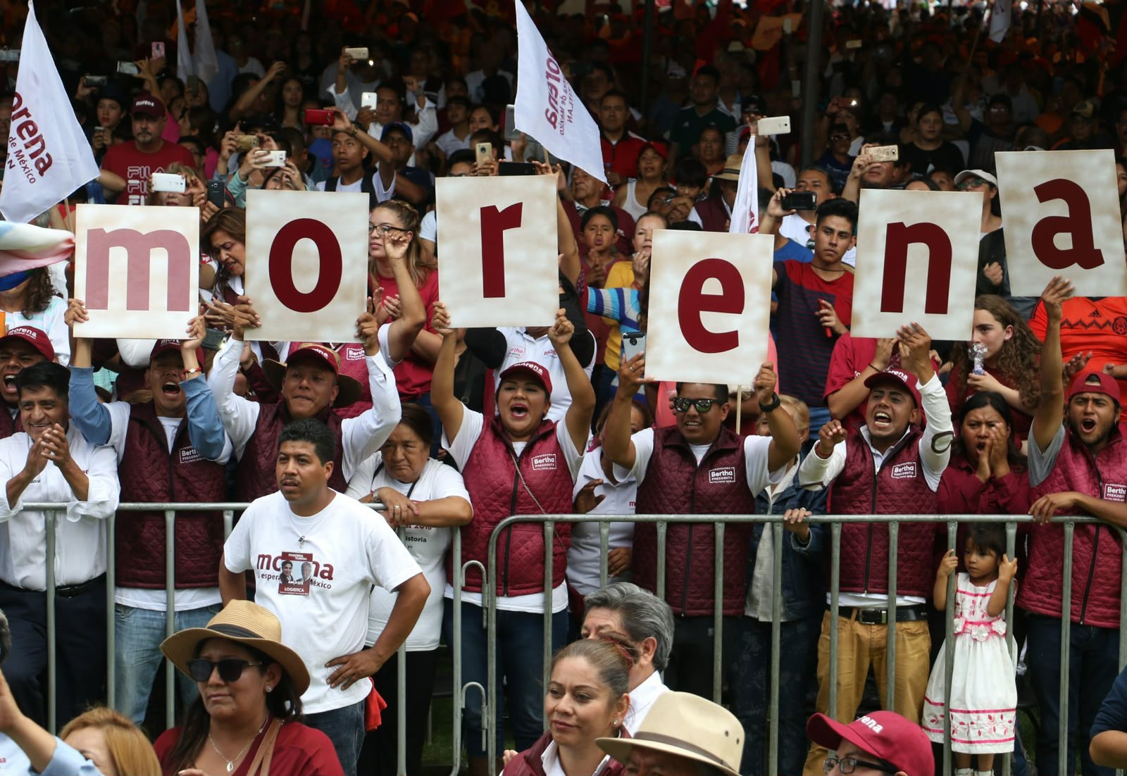 Simpatizantes en un acto público sostienen carteles que forman la palabra Morena