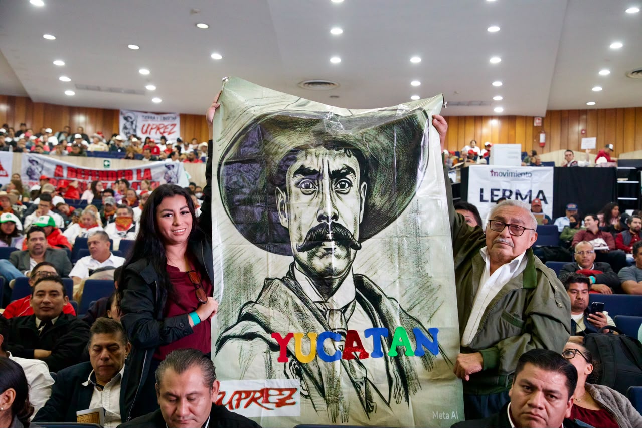 Mujer con lentes habla ante dos micrófonos en un atril con el texto Encuentro Nacional de Movimientos Sociales y Morena.