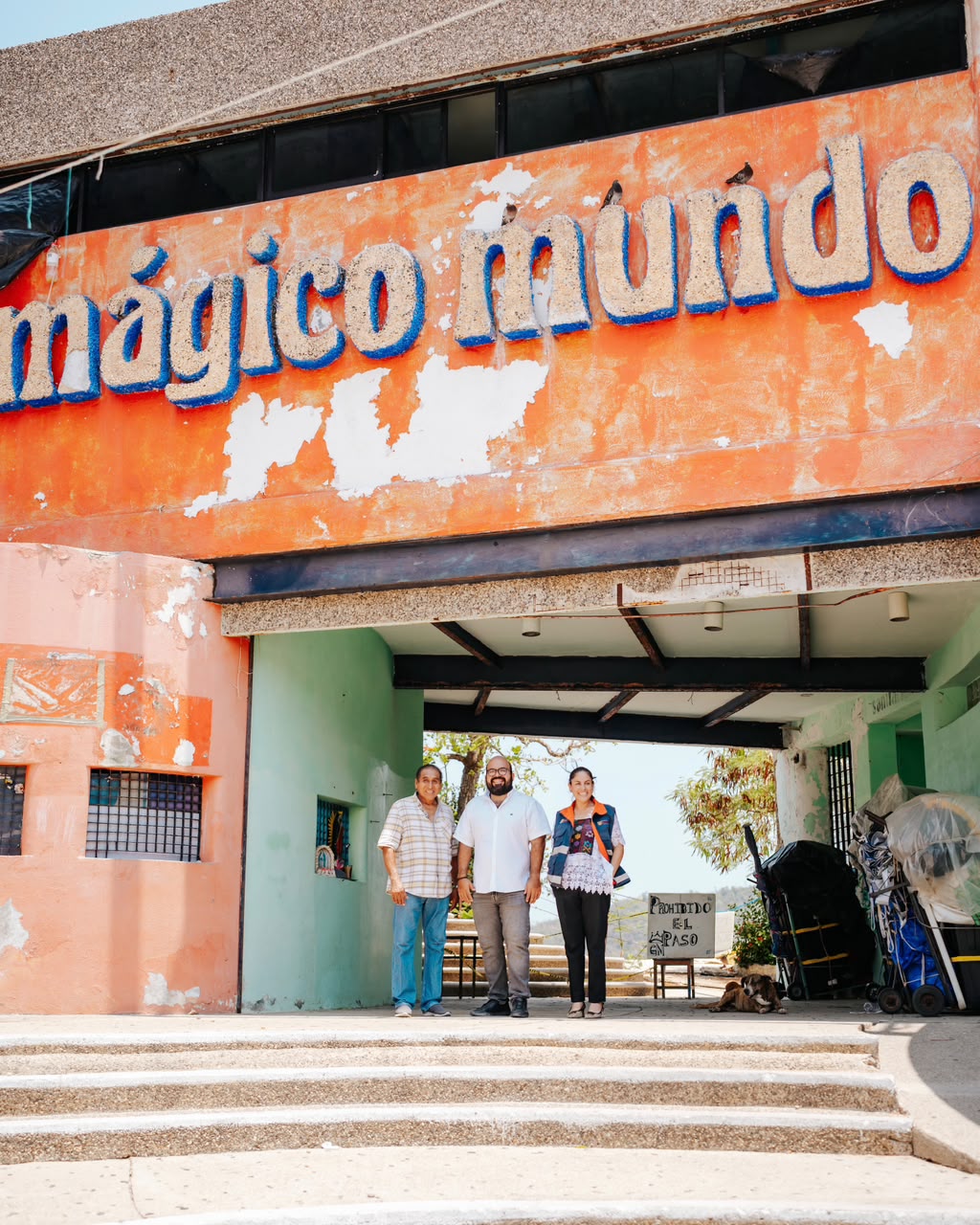 Acceso a Mágico Mundo Marino con letreros del recinto, vegetación y una estructura azul frente al mar