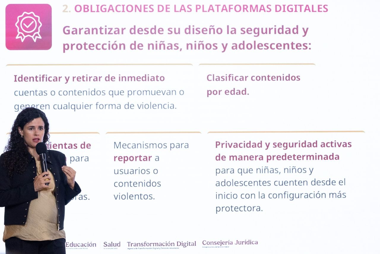 Una expositora sostiene un micrófono frente a una diapositiva sobre obligaciones de las plataformas digitales para proteger a niñas, niños y adolescentes.