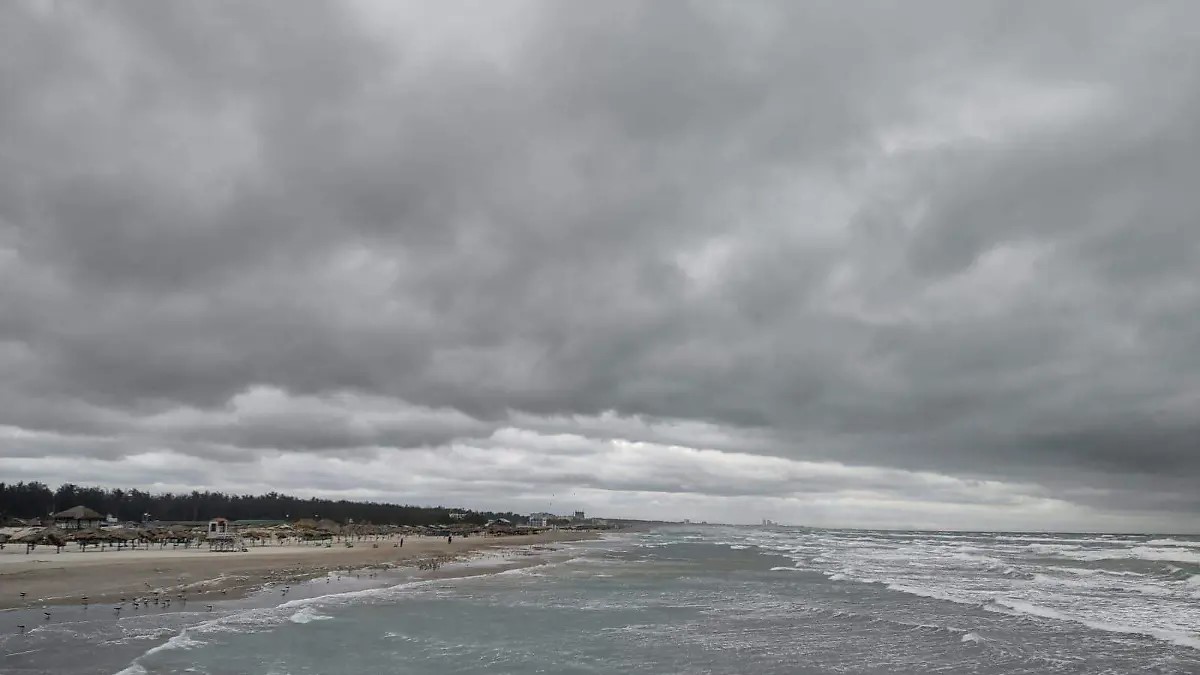 Costa con oleaje elevado bajo un cielo cubierto por nubes oscuras