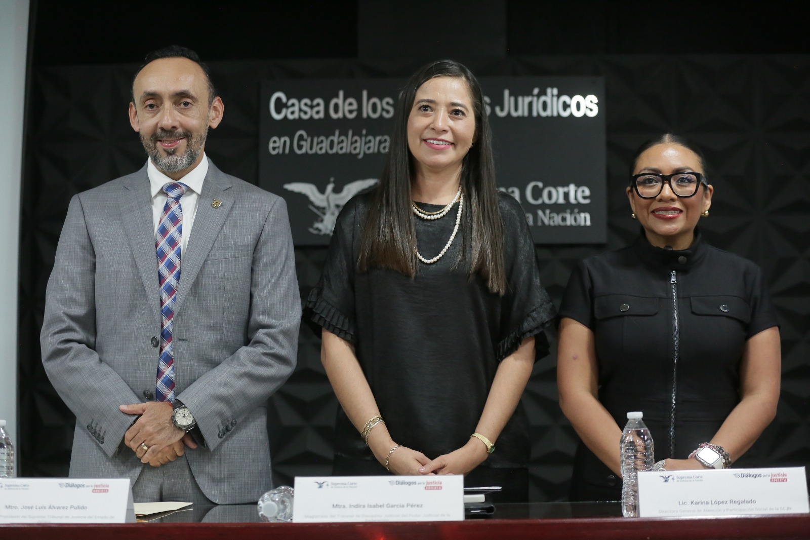 Tres participantes posan frente a un letrero de la Casa de los Saberes Jurídicos en Guadalajara durante un encuentro de justicia abierta