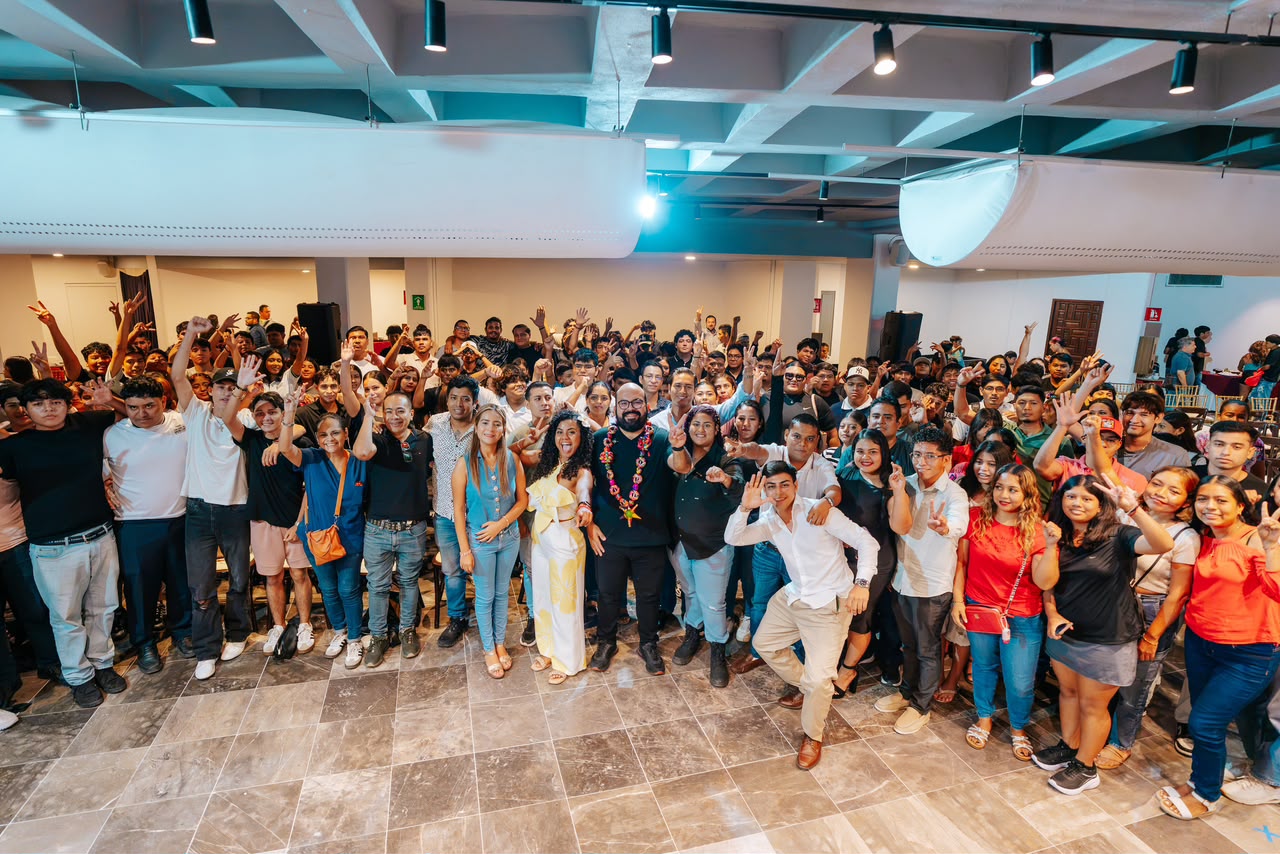 Grupo numeroso de jóvenes y adultos reunidos en un salón para una fotografía colectiva