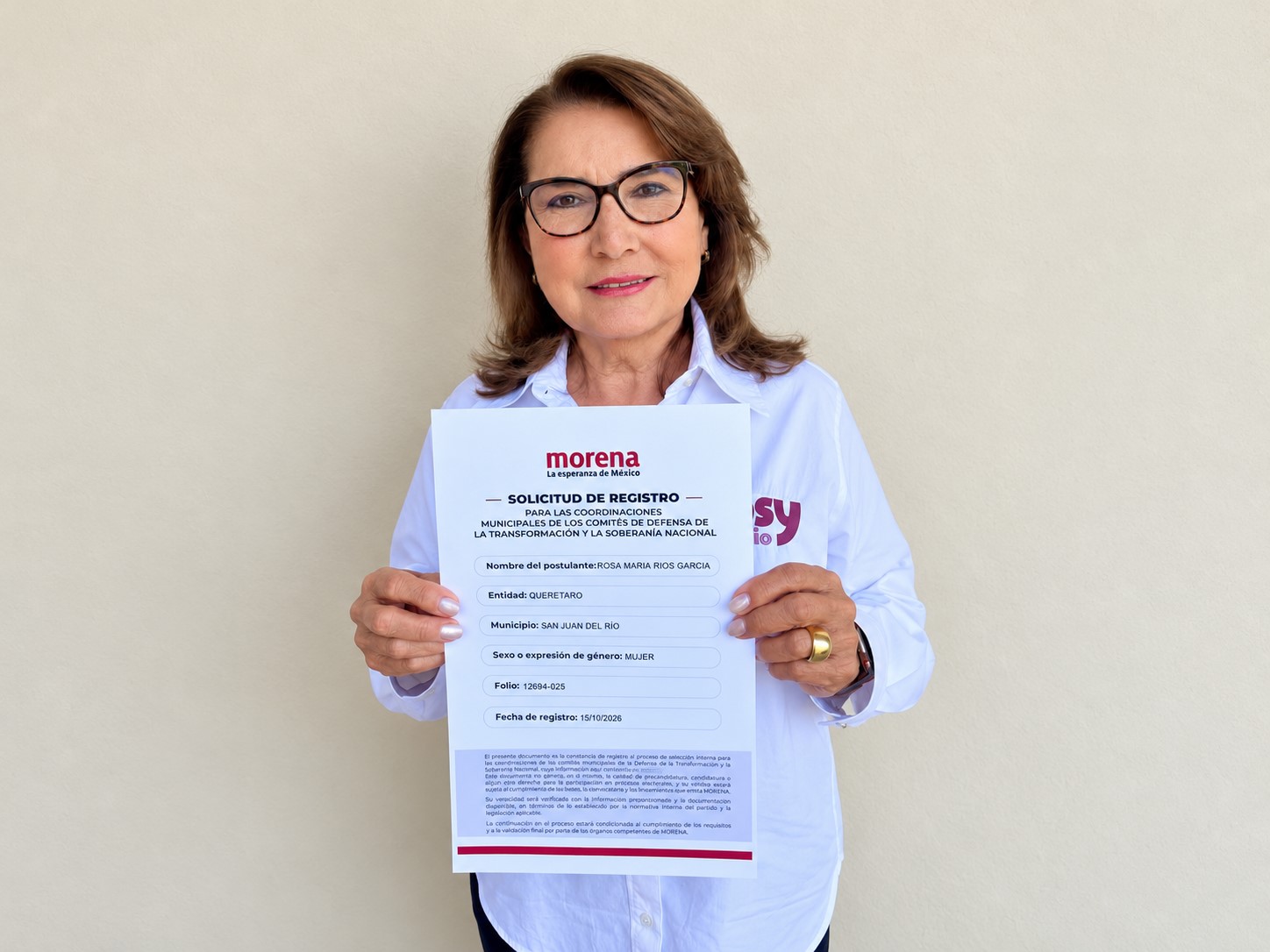 Rosa María Ríos García sostiene una solicitud de registro de Morena frente a una pared clara