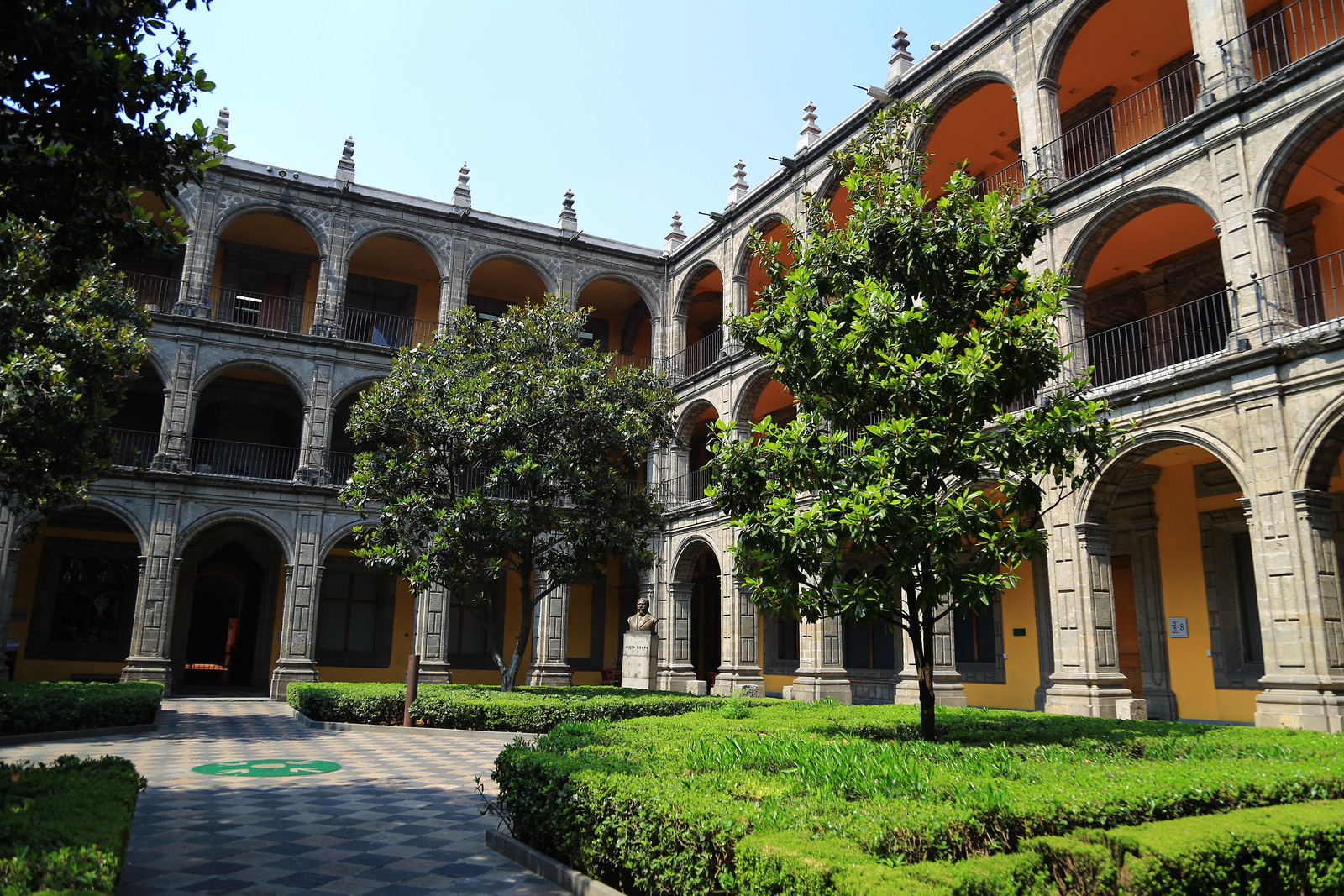 Patio histórico con arquerías de piedra, árboles y jardines