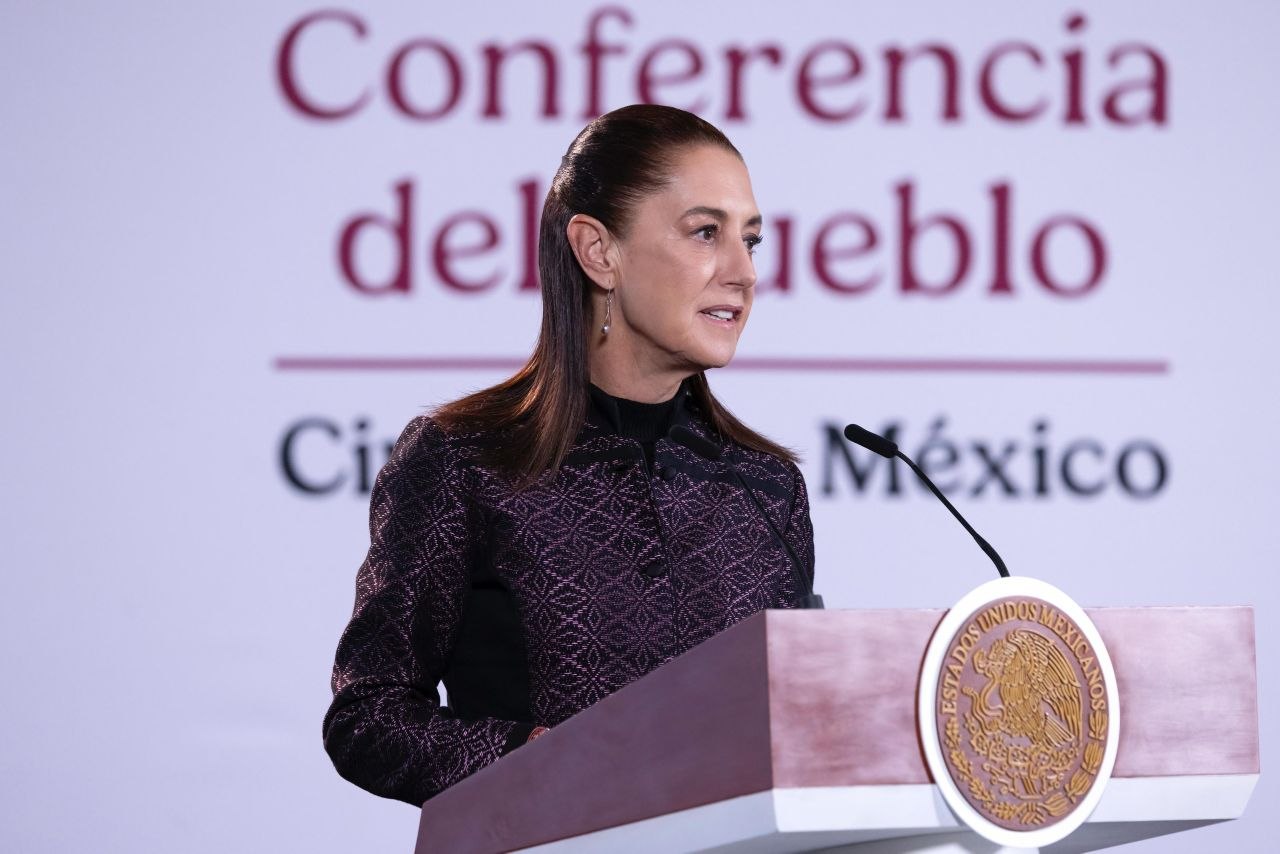 Mujer habla desde un podio oficial con el Escudo Nacional durante una conferencia
