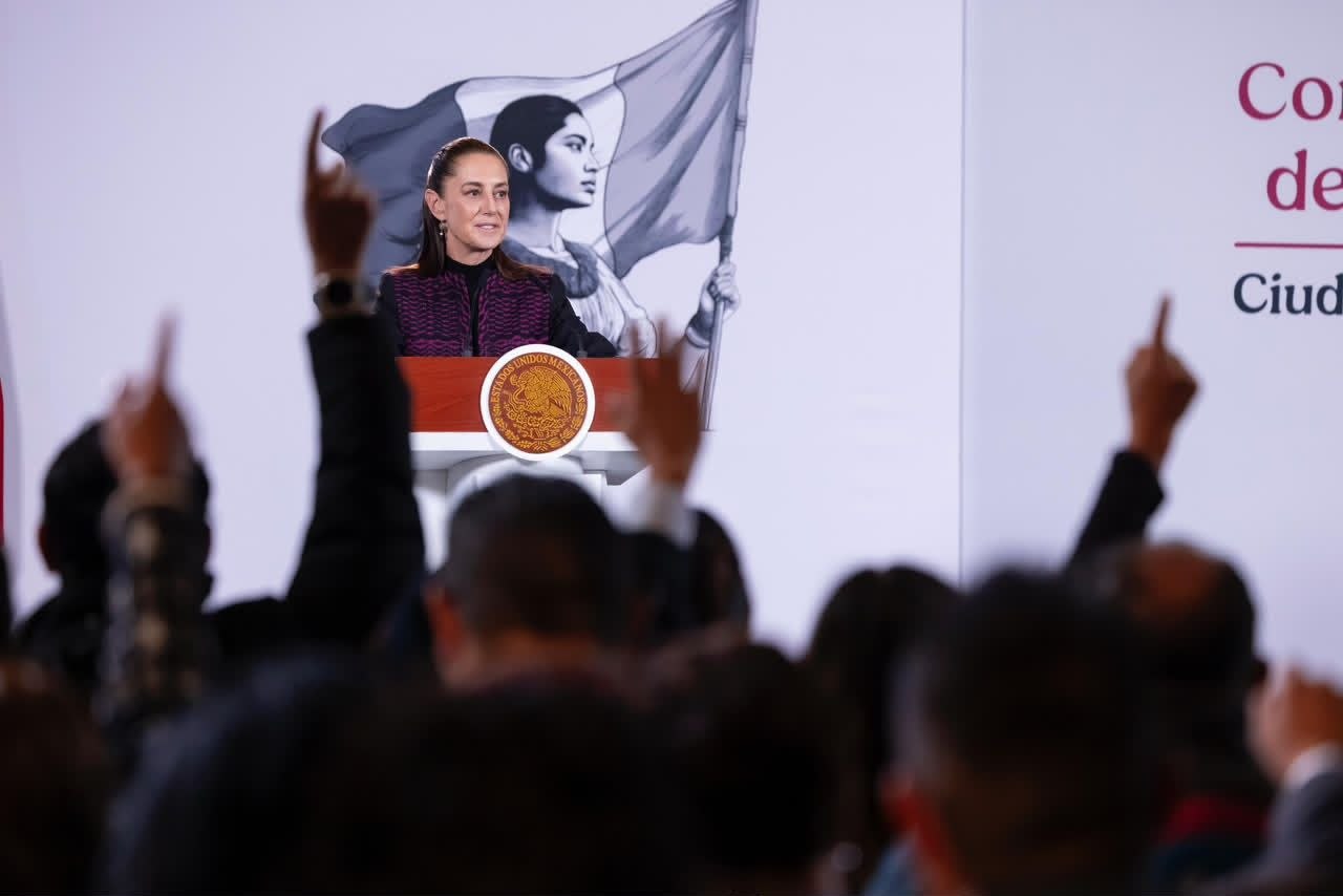 Claudia Sheinbaum habla desde un podio durante una conferencia, con asistentes al frente.