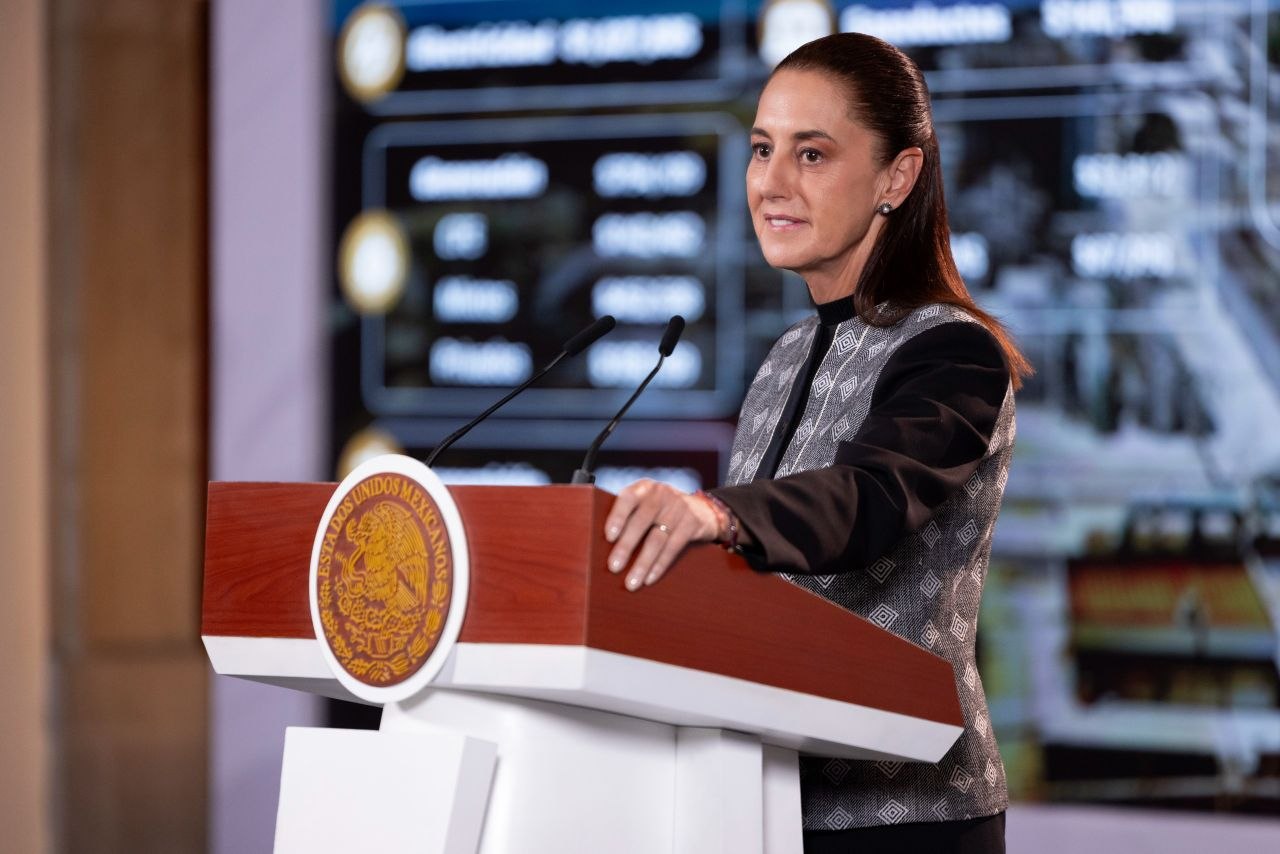 Presidenta de México frente a dos micrófonos en un podio con el escudo nacional