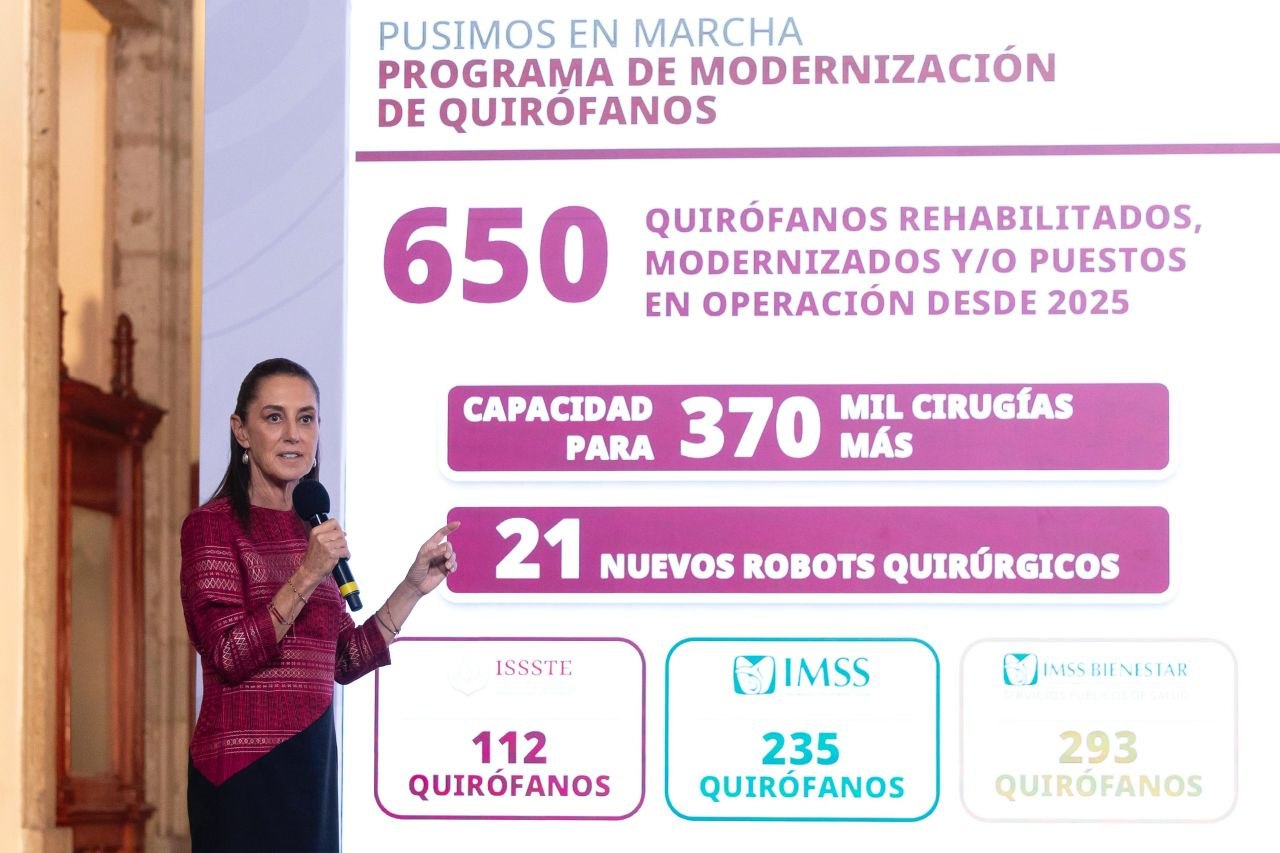 Claudia Sheinbaum habla con un micrófono junto a una pantalla con cifras sobre modernización de quirófanos.